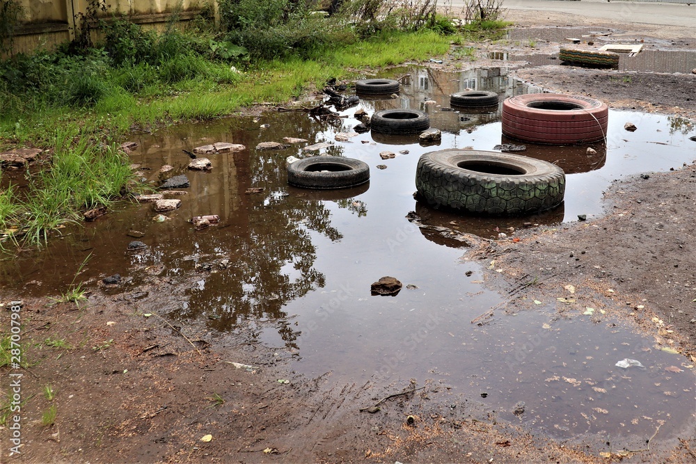old car tires of different sizes are in a puddle