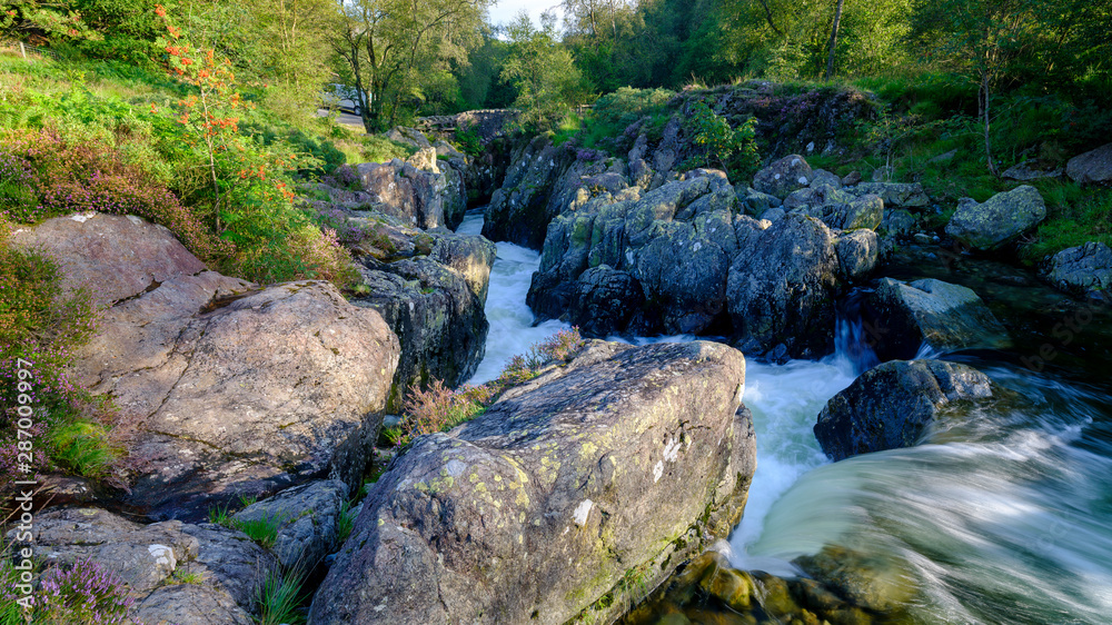 Obraz premium The old packhorse bridge known as Birk's Bridge across the river Duddon near Seathwaite in the Lake District National Park.
