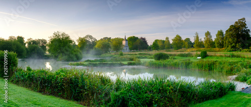 Misty dawn light on Stoke Charity village pond and St Michael's Church, Hampshire, UK photo