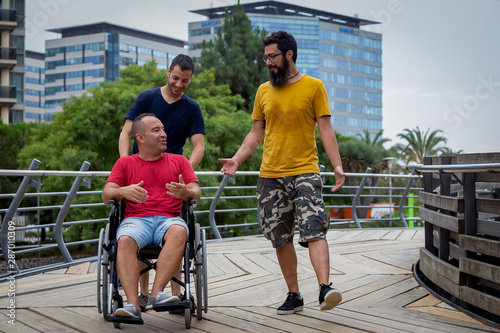 three friends, one on wheelchair walking