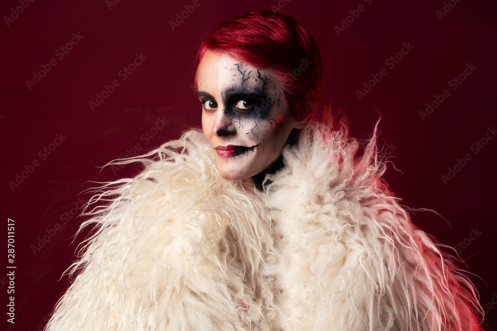 Woman with halloween makeup and red hair wearing white faux fur Woman with halloween makeup and red hair wearing white faux fur