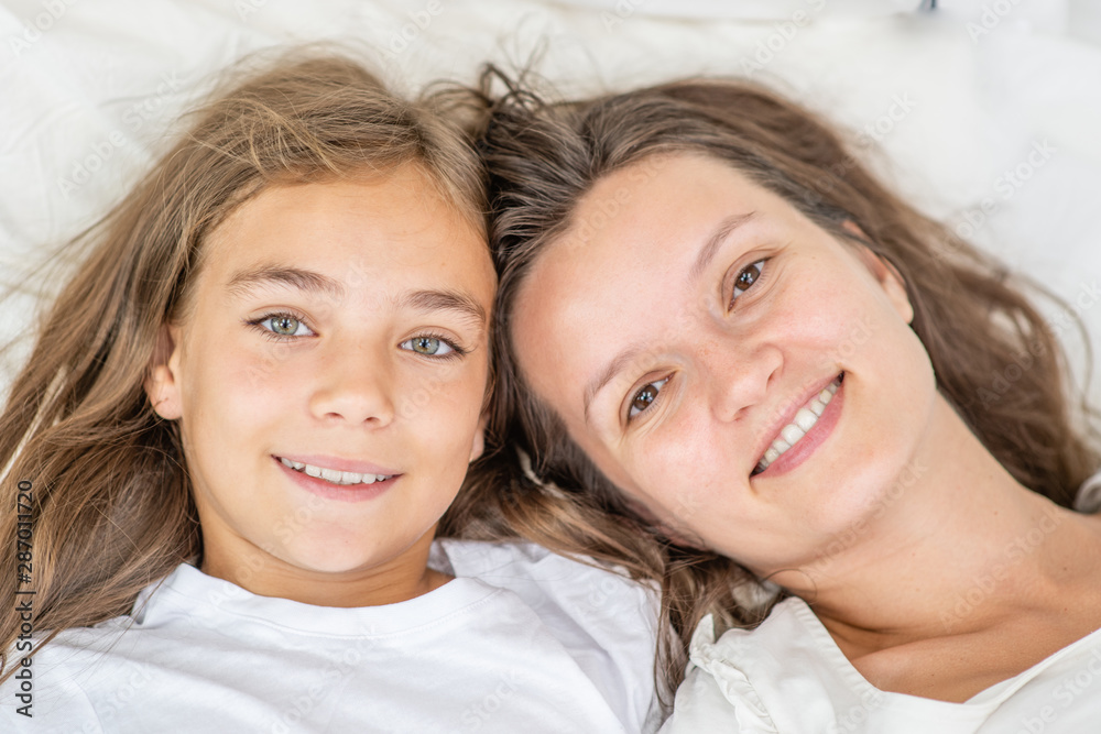 Happy mother with daughter lie on the bed. Top view Happy mother with daughter lie on the bed. Top view
