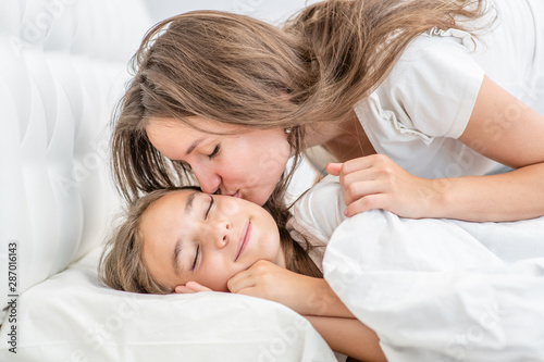 Happy family at home. Mom kisses daughter before bedtime © Ermolaev Alexandr