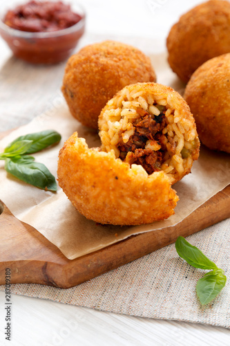 Homemade fried Arancini with basil and Marinara on a white wooden surface, side view. Italian rice balls. Closeup. photo