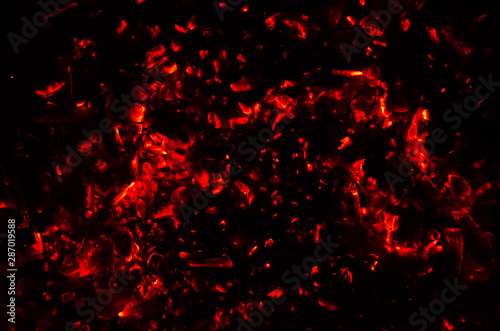 Actively smoldering embers of fire. Background of burning hot coals. Flicker of burning coals at night