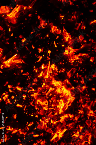 Actively smoldering embers of fire. Background of burning hot coals. Flicker of burning coals at night