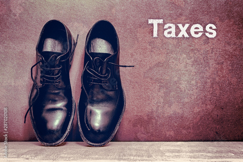 Taxes on brown board and work shoes on wooden floor