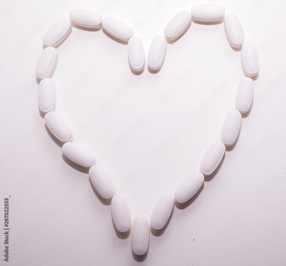 White oval heart shaped pills closse to each other as a background for pharmacy concept. White oval heart shaped pills closse to each other as a background for pharmacy concept.