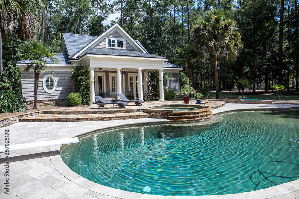Custom pool House behind a landscaped estate with a large swimming pool and hot tub