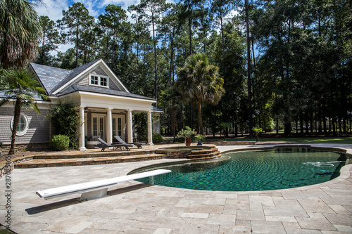Bild auf Leinwand Custom pool House behind a landscaped estate with a large swimming pool and hot