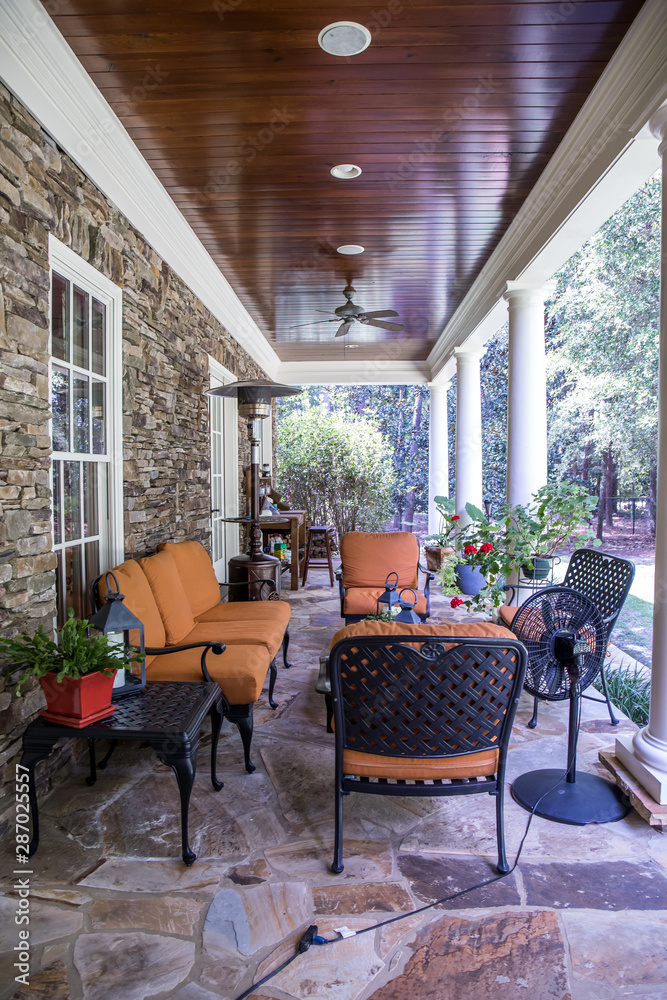 Φωτογραφία Outdoor Stone Patio Porch of large home estate with orange rust colorseating