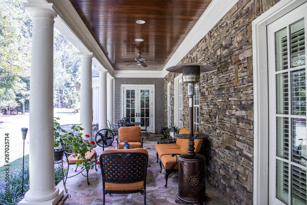 Φωτογραφία Outdoor Stone Patio Porch of large home estate with orange rust colorseating