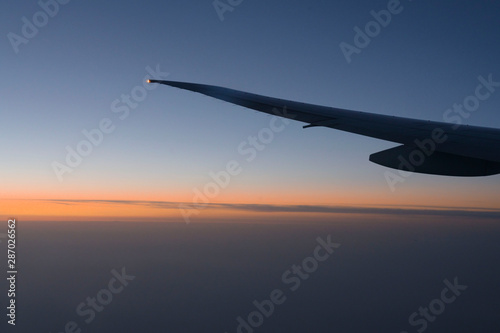 Plane wing light on the sky in earling morning with the sunrise line sky background