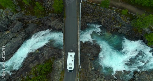 Aerial: Drone shot of camper van on bridge over flowing river - Oppland, Sweden photo