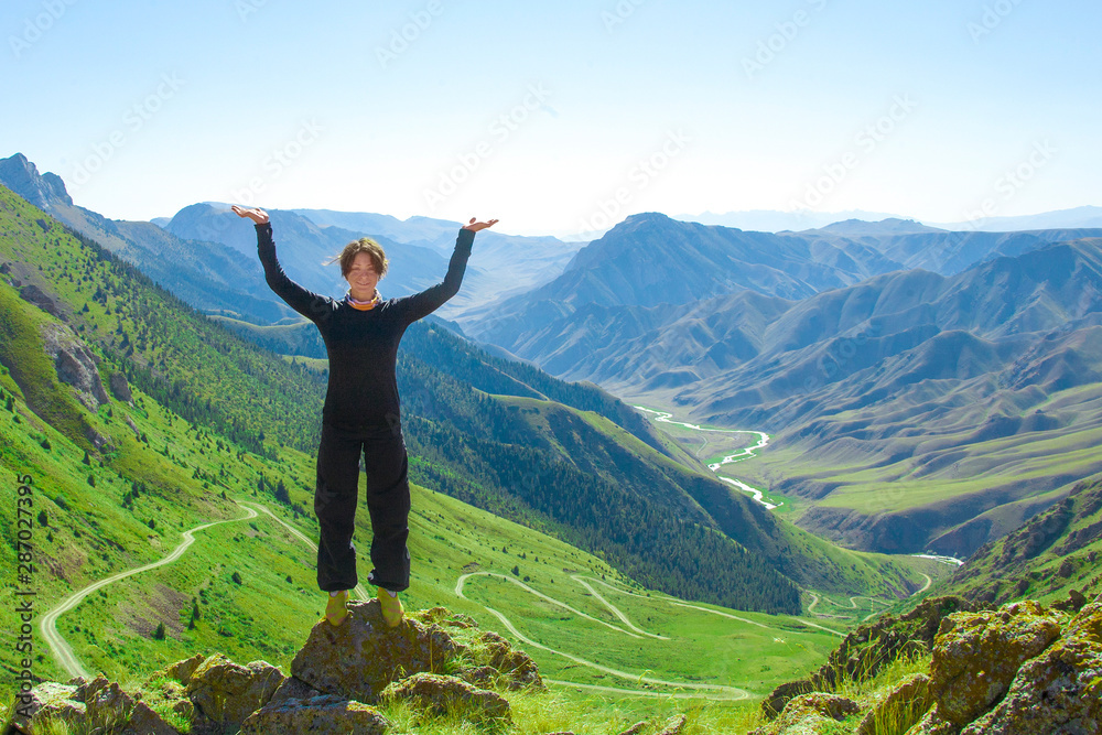 Girl with hands up in the mountains.