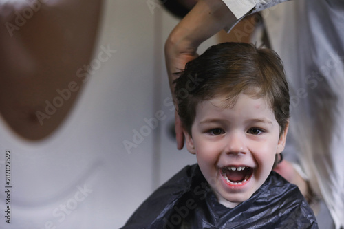 Hairdresser and boy. The boy is doing his hair. Cut hair child in the hairdresser.