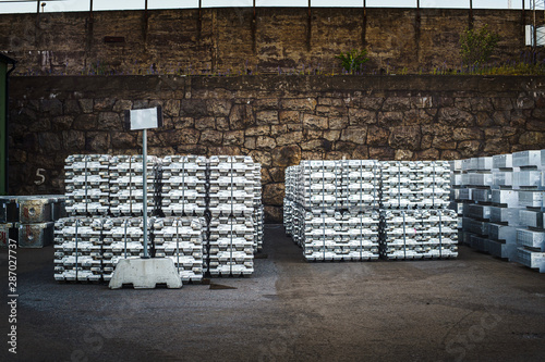 Cargo at the port. Aluminum ingots on the pier. Against the background of cargo depots and ships. photo