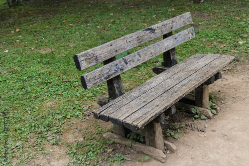 Wooden bench in the park with the grass on the background - Image