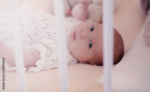 Mom with a newborn baby in her arms. The girl is holding a baby in front of the window. Newborn on mother's hands.