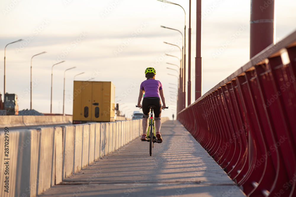 Bright colorful photo of recognizable bicycle rider moving on urban landscape in sunlight