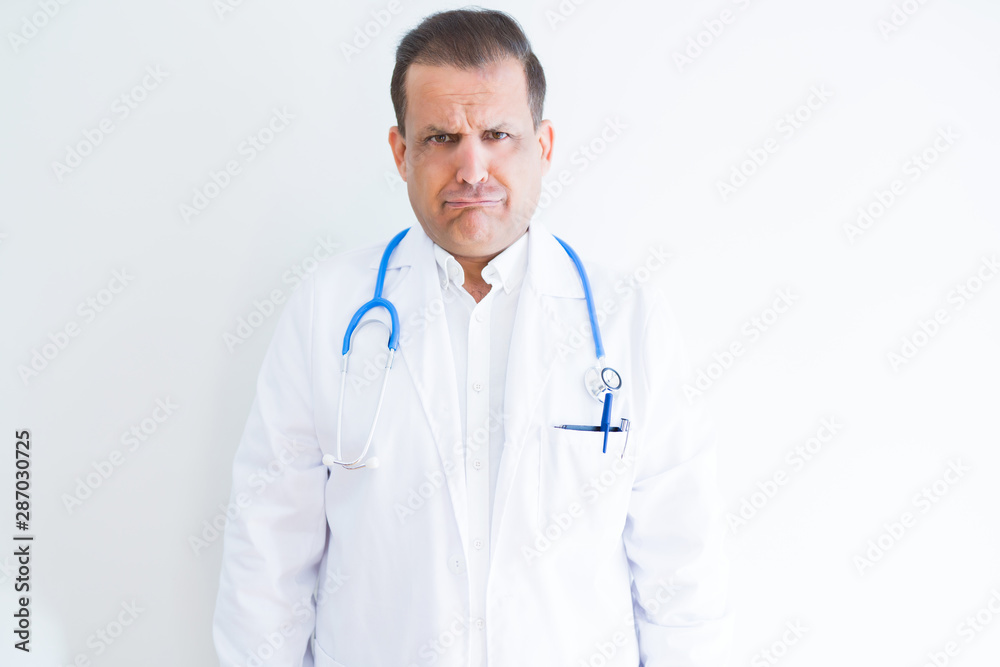 Middle age doctor man wearing stethoscope and medical coat over white background depressed and worry for distress, crying angry and afraid. Sad expression. Middle age doctor man wearing stethoscope and medical coat over white background depressed and worry for distress, crying angry and afraid. Sad expression.