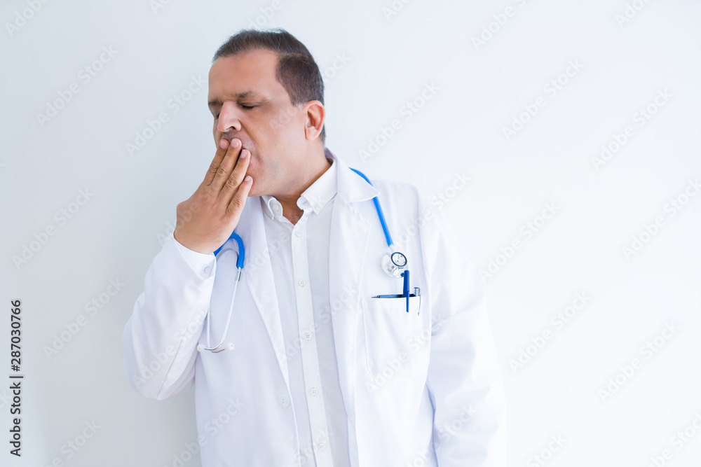 Middle age doctor man wearing stethoscope and medical coat over white background bored yawning tired covering mouth with hand. Restless and sleepiness. Middle age doctor man wearing stethoscope and medical coat over white background bored yawning tired covering mouth with hand. Restless and sleepiness.