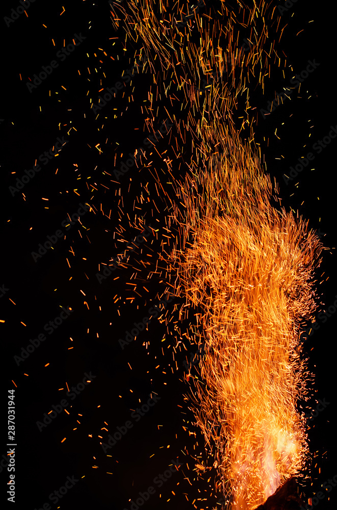 Flame of fire with flying burning red sparks on a black background ...