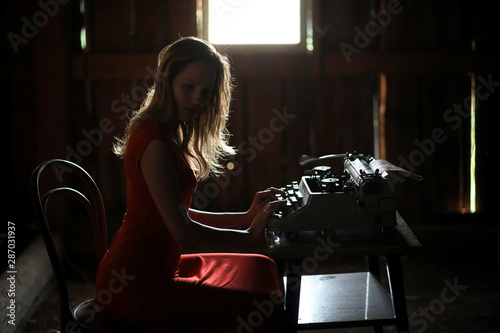 A girl in retro style prints on an old typewriter