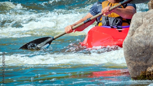 Playboating. A man sitting in a kayak with oars in his hands performs exercises on the water. Kayaking freestyle on whitewater.