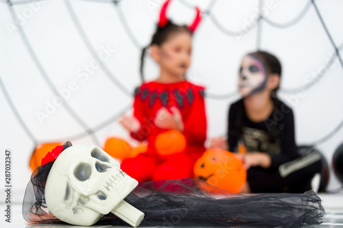Halloween background with skulls on the front and with blurred photo Little girl in halloween carnival costume in back.