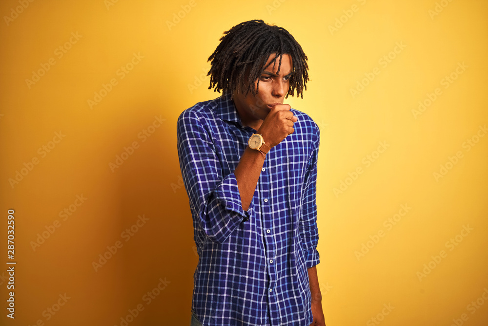 Afro man with dreadlocks wearing casual shirt standing over isolated yellow background feeling unwell and coughing as symptom for cold or bronchitis. Healthcare concept. Afro man with dreadlocks wearing casual shirt standing over isolated yellow background feeling unwell and coughing as symptom for cold or bronchitis. Healthcare concept.