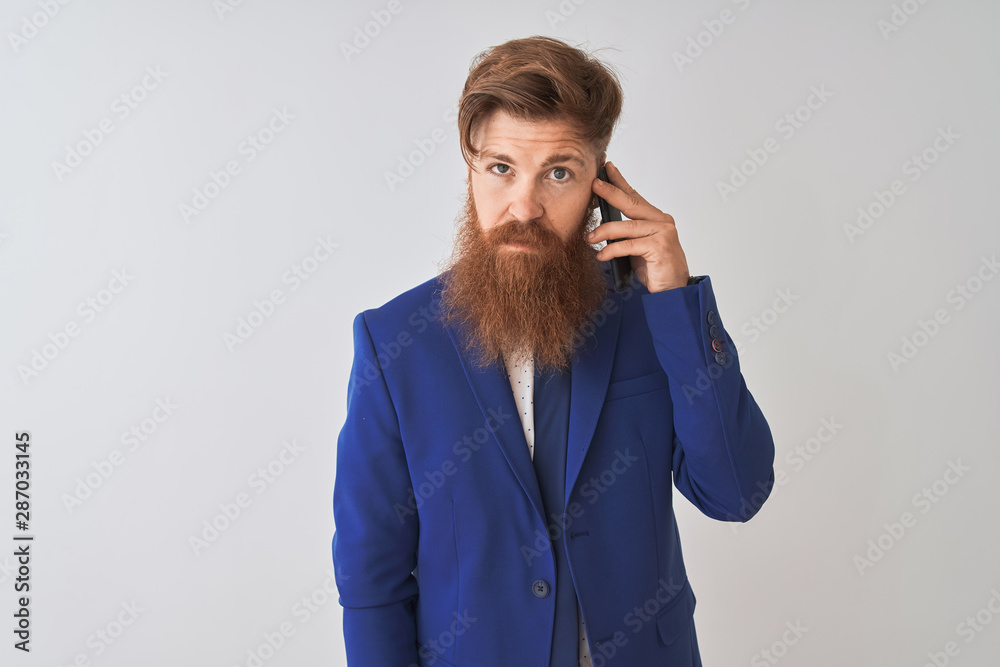 Young redhead irish businessman talking on the smartphone over isolated white background with a confident expression on smart face thinking serious Young redhead irish businessman talking on the smartphone over isolated white background with a confident expression on smart face thinking serious