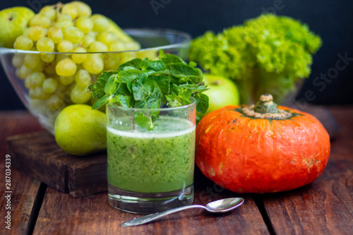 Diet drink, smoothie. Green color. Body cleansing. Diet. Nearby are orange pumpkin, pears, apple, mint leaves, pepper. Lobules of Lemon. A bunch of white grapes. Healthy eating Light breakfast. 