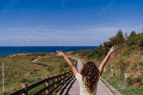 young woman outdoors Enjoying a sunny and windy day. Fun, summertime and holidays concept. Back view