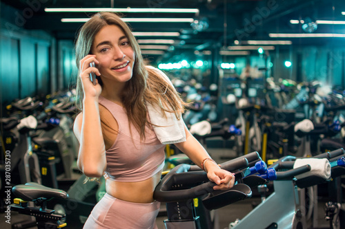 Smiling young woman using phone after cycling training in a spin studio