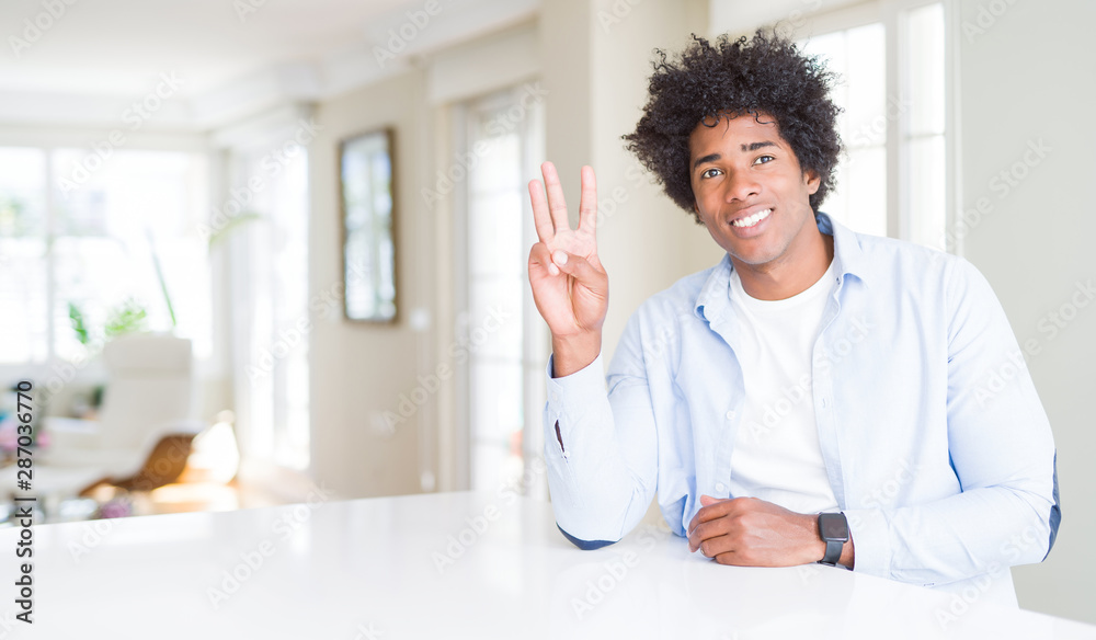 African American man at home showing and pointing up with fingers number three while smiling confident and happy. African American man at home showing and pointing up with fingers number three while smiling confident and happy.