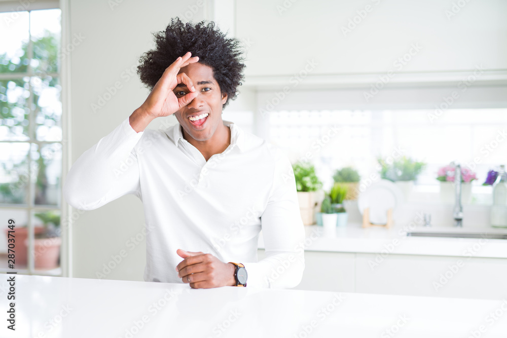 African American man doing ok gesture with hand smiling, eye looking through fingers with happy face.