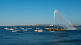 Geyser forming a rainbow on River Tagus with fishing boats overlooking 25 April Bridge and Rei Cristo statue in Lisbon, Portugal