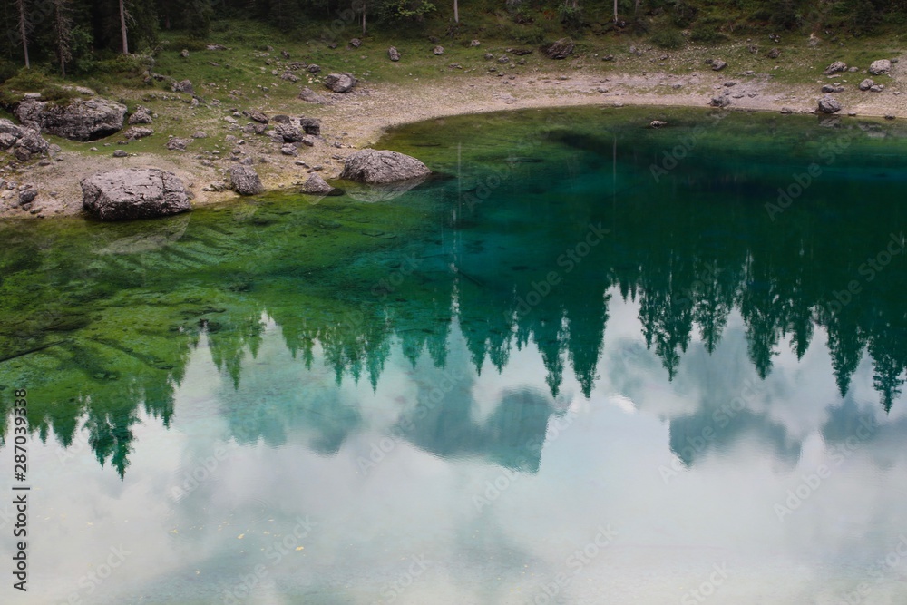 Lake Carezza, mountain lake famous for the dark green color and the beautiful panorama of mountains in the background. Reflection of the Rose Garden in the Lake. South Tirol, Italy Lake Carezza, mountain lake famous for the dark green color and the beautiful panorama of mountains in the background. Reflection of the Rose Garden in the Lake. South Tirol, Italy