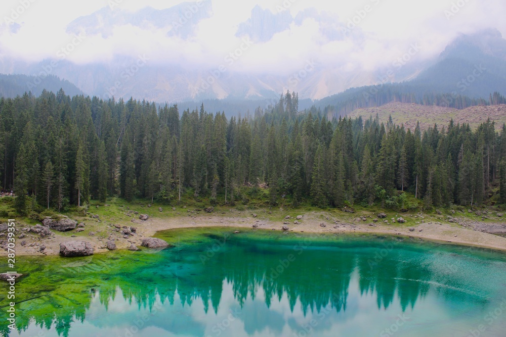 Fototapeta premium Lake Carezza, the small mountain lake is famous for the dark green color, and the beautiful panorama of mountains in the background. Legend of King Laurin and his Rosegarden. South Tyrol, Italy. I