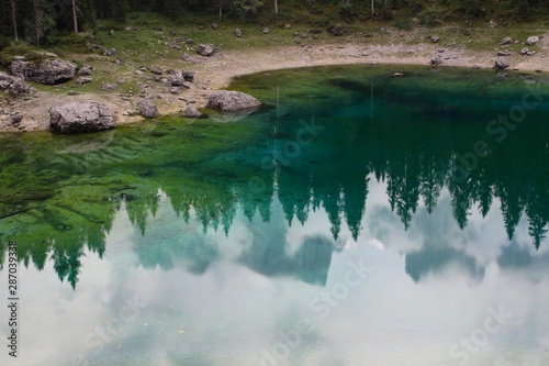 Lake Carezza, mountain lake famous for the dark green color and the beautiful panorama of mountains in the background. Reflection of the Rose Garden in the Lake. South Tirol, Italy