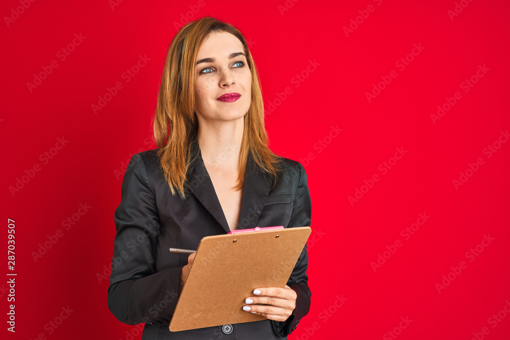 Fototapeta premium Young beautiful redhead businesswoman wearing suit writing on flip board
