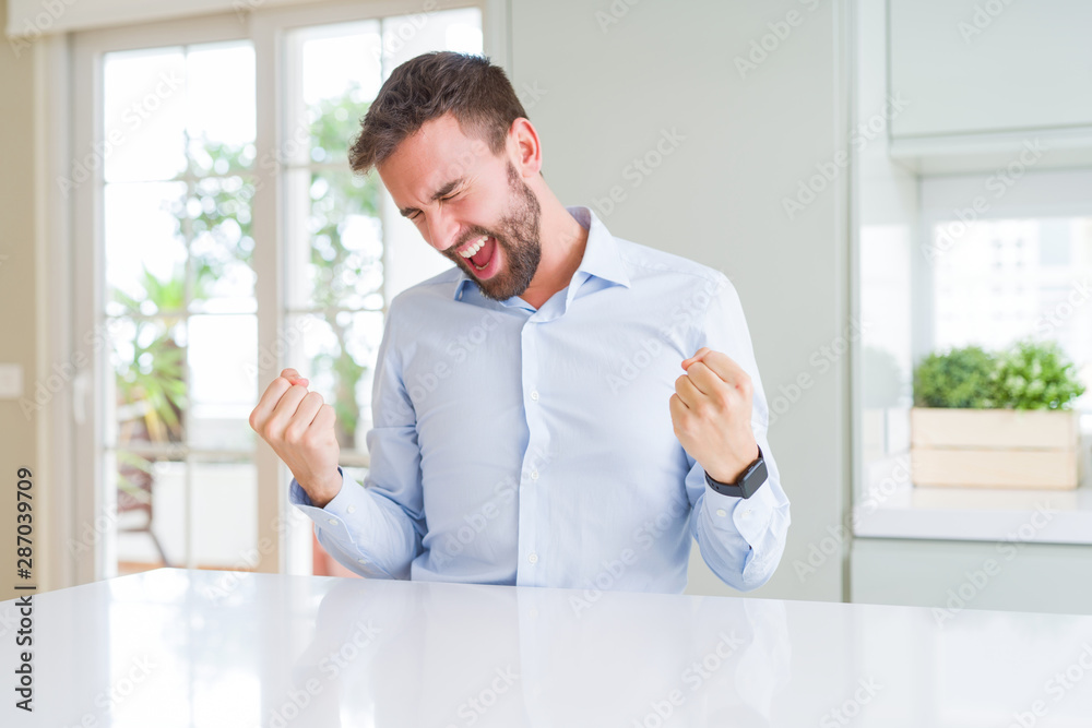 Handsome business man very happy and excited doing winner gesture with arms raised, smiling and screaming for success. Celebration concept. Handsome business man very happy and excited doing winner gesture with arms raised, smiling and screaming for success. Celebration concept.