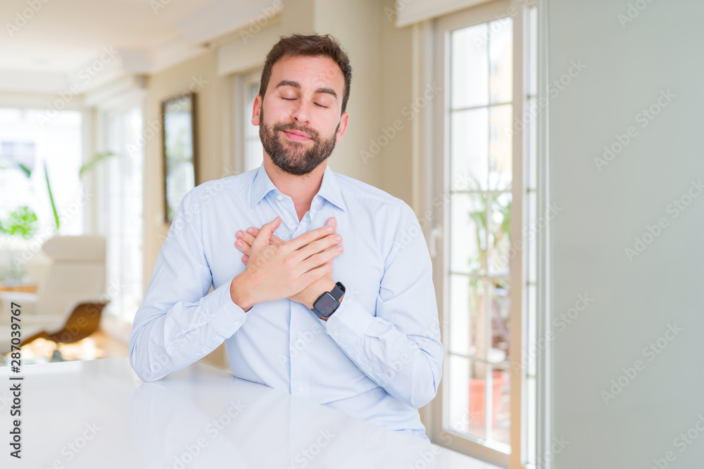 Handsome business man smiling with hands on chest with closed eyes and grateful gesture on face. Health concept.