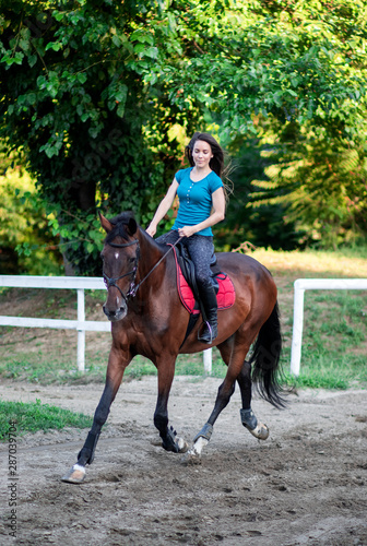 Young beautiful brunette girl riding on a horse.