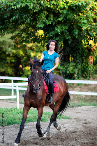 Young beautiful brunette girl riding on a horse. © Andrej