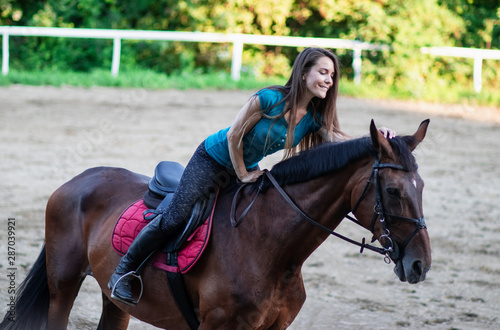 Young beautiful long hair brunette girl poses on a horse.