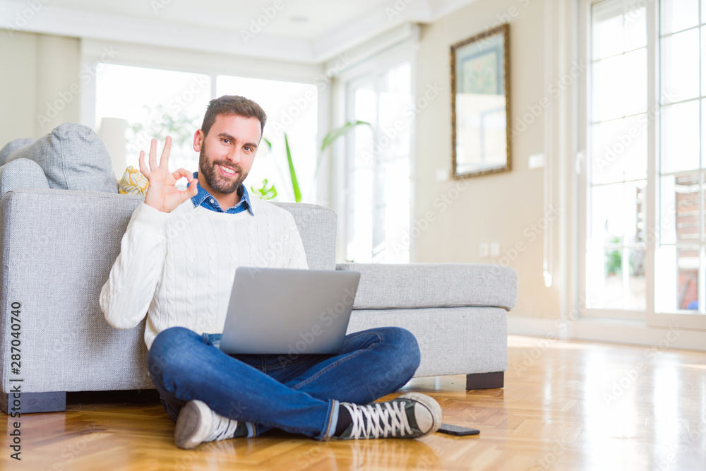 Handsome man wearing working using computer laptop doing ok sign with fingers, excellent symbol Handsome man wearing working using computer laptop doing ok sign with fingers, excellent symbol
