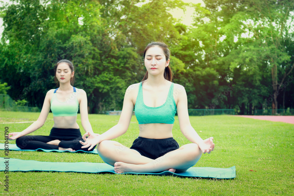 Two pretty Asian teen women are practicing yoga in the garden park at nature, sport females are doing exercises outdoor, fitness and healthy lifestyle concept. Two pretty Asian teen women are practicing yoga in the garden park at nature, sport females are doing exercises outdoor, fitness and healthy lifestyle concept.