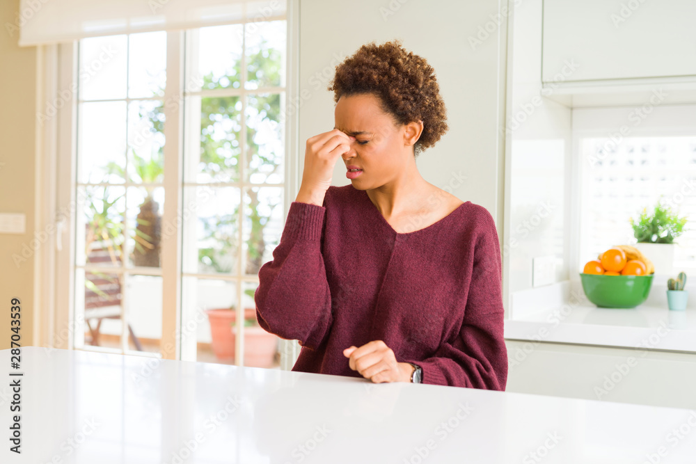 Young beautiful african american woman at home tired rubbing nose and eyes feeling fatigue and headache. Stress and frustration concept. Young beautiful african american woman at home tired rubbing nose and eyes feeling fatigue and headache. Stress and frustration concept.